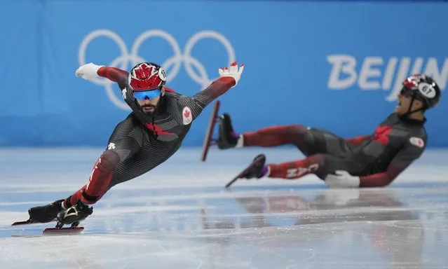 Jordan Pierre-Gilles of Canada, crashes out of his races in his men's 500-meters quarterfinal as compatriot Steven Dubois races ahead during the short track speedskating competition at the 2022 Winter Olympics, Sunday, February 13, 2022, in Beijing. (Photo by Bernat Armangue/AP Photo)