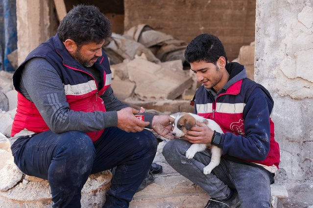 In this picture taken on February 24, 2023, volunteer Mohammed Alaa al-Jalil (L) and his colleague rescue a dog from the rubble of an earthquake-devasted building in Jindayris, in the rebel-held Syrian province of Aleppo. A 7.8-magnitude quake struck Syria and Turkey in early February, killing more than 45,000 people across both countries. (Photo by Rami al Sayed/AFP Photo)
