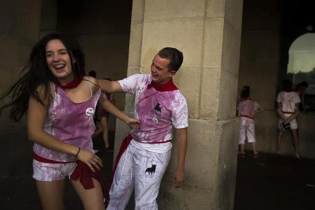 Revelers with their clothes covered in wine laugh during the San Fermin festival, in Pamplona, Spain, Tuesday, July 7, 2015. (Photo by Andres Kudacki/AP Photo)