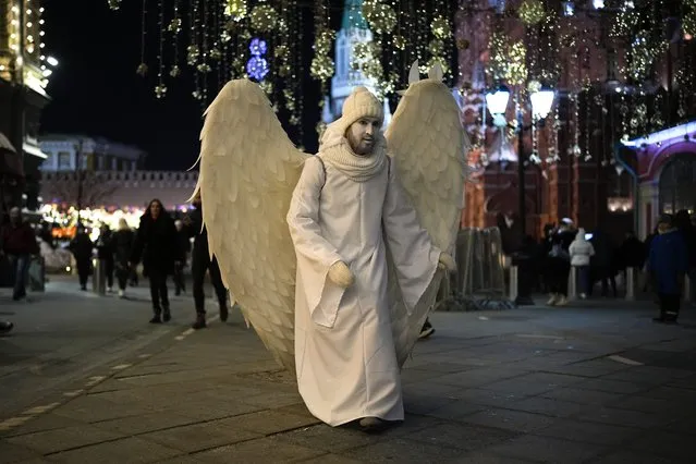 A street actor dressed as an angel walks near Red Square in Moscow, Russia, late Monday, February 14, 2022. (Photo by Alexander Zemlianichenko/AP Photo)