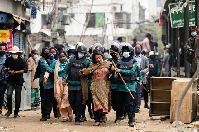 Police detain women as they were interfering with authorities during the demolition of buildings illegally built on government properties in Dhaka on January 23, 2022. (Photo by Munir Uz Zaman/AFP Photo)
