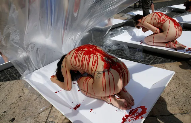 Animal rights activists prepare to be wrapped in packaging labelled “carne humana” (human meat) as they participate in a protest against meat consumption to promote vegetarianism in central Barcelona, in Spain, May 22, 2016. (Photo by Albert Gea/Reuters)