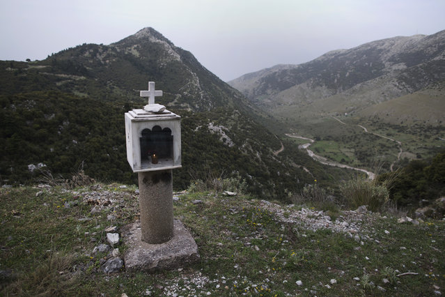 In this photo taken on Saturday, April 29, 2017, a candle is lit in a roadside shrine near the at the village of Agia Kiriaki, in the Peloponnese region of southern Greece. (Photo by Petros Giannakouris/AP Photo)