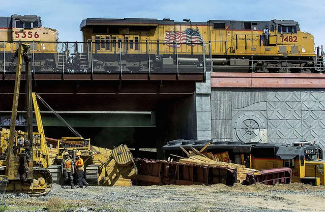 A Union Pacific Railroad train engineer looks down from above as a train passes the derailed train near 5th and K streets in Colton, Calif., on Monday, March 21, 2022. (Photo by Terry Pierson/The Orange County Register via AP Photo)