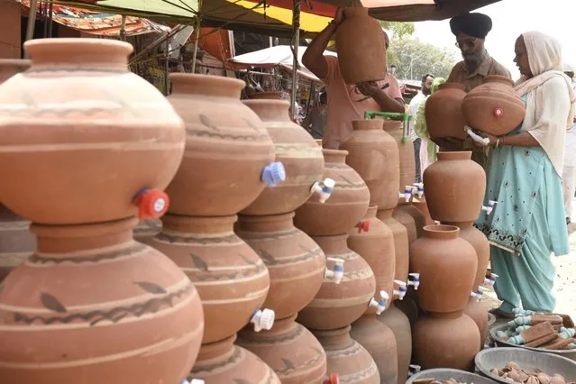 People buy a Matka, an earthen pot used to store cool drinking water, at a roadside stall in Amritsar on April 11, 2022. (Photo by Narinder Nanu/AFP Photo)