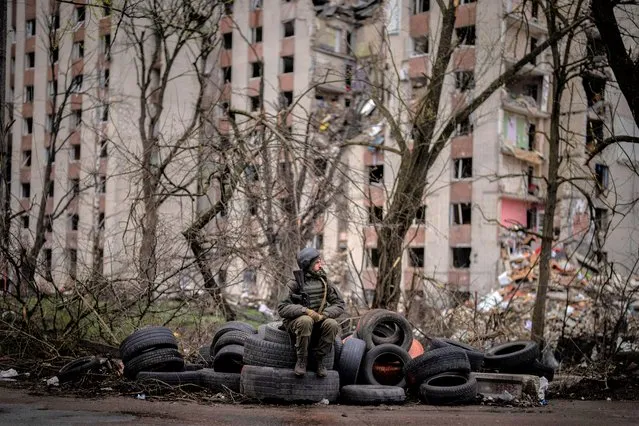 A Ukrainian soldier sits on tyres next to a building destroyed by Russian bombing in Chernihiv on Saturday, April 23, 2022. (Photo by Emilio Morenatti/AP Photo)