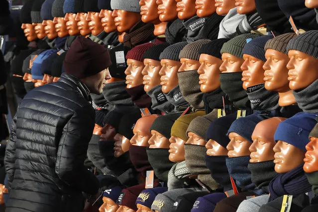 A man looks at himself in a mirror, hidden between mannequins, as he chooses a cap at the clothing market in Minsk, Belarus, Wednesday, October 30, 2019. (Photo by Sergei Grits/AP Photo)