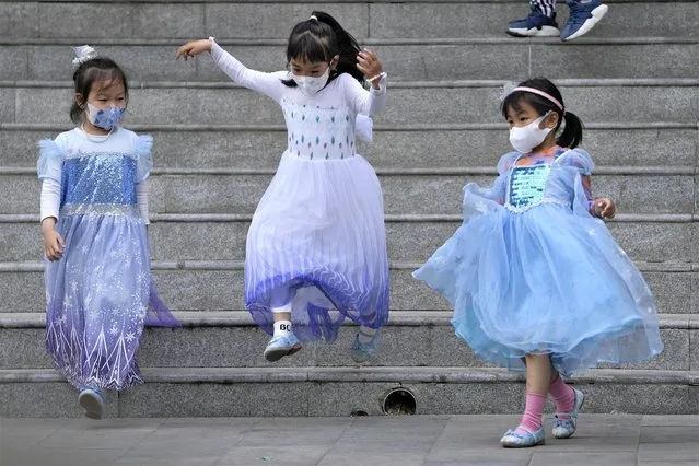 Children wearing princess dresses and face masks play on a staircases on Wednesday, May 18, 2022, in Beijing. (Photo by Andy Wong/AP Photo)