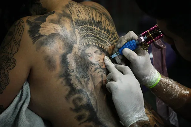 A tattoo artist makes a tattoo on the back of a young woman during the Tattoo Week in Sao Paulo, Brazil, July 14, 2017. (Photo by Imago via ZUMA Press)