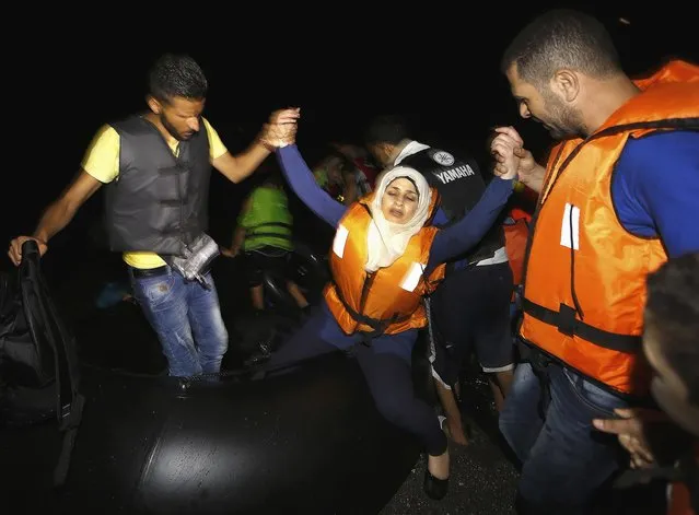 Syrian refugees help a woman off a dinghy  as they arrive at a beach on the Greek island of Kos, August 12, 2015. The United Nations refugee agency (UNHCR) called on Greece to take control of the “total chaos” on Mediterranean islands, where thousands of migrants have landed. About 124,000 have arrived this year by sea, many via Turkey, according to Vincent Cochetel, UNHCR director for Europe. (Photo by Yannis Behrakis/Reuters)