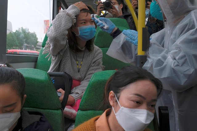 A resident wearing mask and raincoat volunteers to take temperature of passenger following the outbreak of a new coronavirus at a bus stop at Tin Shui Wai, a border town in Hong Kong, China on February 4, 2020. (Photo by Tyrone Siu/Reuters)