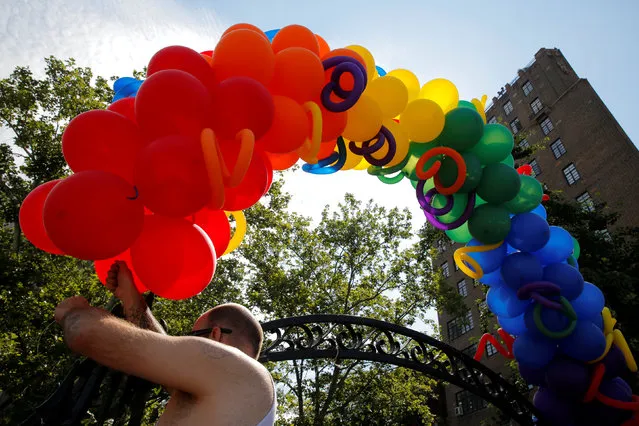 A man hangs balloons on the entrance of Christopher Park ahead of a ceremony officially designating it and The Stonewall Inn and as part of the Stonewall National Monument in the Manhattan borough of New York, U.S., June 27, 2016. (Photo by Andrew Kelly/Reuters)