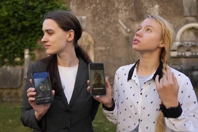 Kateryna Prokopenko, wife of Denys Prokopenko, commander of the Azov regiment, right, and Yulia Fedosiuk, wife of Arseny Fedosiuk, another member of Azov regiment get emotional as they show photos of their husbands on their phones during an interview with the Associated Press in Rome, Friday, April 29, 2022. Two Ukrainian women whose husbands are defending a besieged steel plant in the southern city of Mariupol are calling for any evacuation of civilians to also include soldiers. They say the troops stand to be tortured and killed if left behind and captured by Russian forces. (Photo by Alessandra Tarantino/AP Photo)