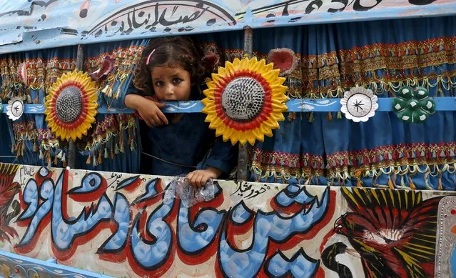 A child looks out of the window of a pickup truck being used as a taxi in Peshawar, Pakistan August 18, 2015. (Photo by Khuram Parvez/Reuters)