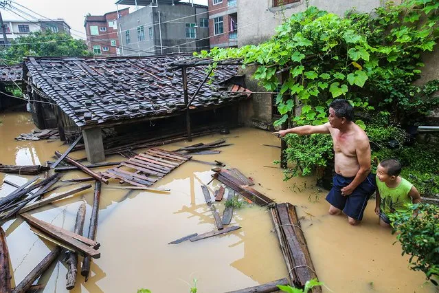 Residents look at an inundated house as they stand in floodwaters in Putian, in eastern China's Fujian province on July 9, 2016. A tropical storm made landfall in China on July 9, the country's national meteorological center said, a day after Super Typhoon Nepartak lashed Taiwan with powerful winds and torrential rain. (Photo by AFP Photo/Stringer)