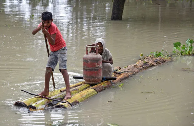 A boy rows a makeshift raft as he transports a woman and a cooking gas cylinder through the flood waters in Morigaon district in Assam, August 18, 2017. (Photo by Anuwar Hazarika/Reuters)