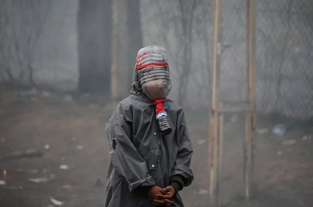 An asylum seeker wears bottle of water as a mask to not to effect by tear gas in the region between the Kastanies and the Pazarkule border gates on March 08, 2020. Thousands of asylum seekers have since flocked to Turkeyâs Edirne province which borders Greece and Bulgaria to make their way to Europe. (Photo by Onur Coban/Anadolu Agency via Getty Images)