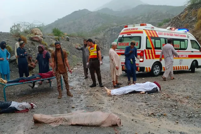 In this photo provided by the Baluchistan Rescue Department, rescue workers and volunteers remove bodies they were recovered from the wreck of a passenger bus that slid off mountain road and fell into a deep ravine, in Zhob, Baluchistan province, in southwest Pakistan, Sunday, July 3, 2022. An official said the passenger bus slid off a mountain road and fell 200 feet (61 meters) into a ravine in heavy rain killing at least 18 people and injuring some 12 others. (Photo by Baluchistan Rescue Department via AP Photo)