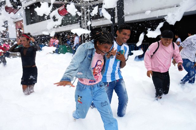 Youth run through foam during an event celebrating University Student Day in Caracas, Venezuela, Thursday, November 21, 2024. (Photo by Ariana Cubillos/AP Photo)