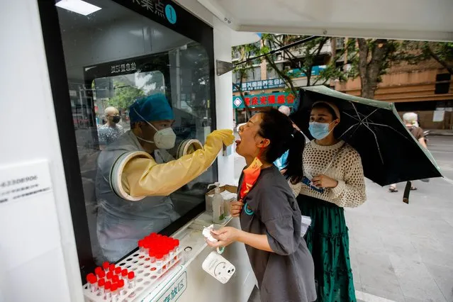 A medical worker takes a swab sample from a woman in Chongqing, China, 29 August 2022. According to the National Health Commission's report on 27 August, 307 new locally transmitted COVID-19 cases were detected in mainland China, of which 12 were in Chongqing. Local Authorities implemented tighter COVID-19 curbs in Chongqing city by imposing mass testing and establishing temporary control areas in the city. (Photo by Wu Hao/EPA/EFE)