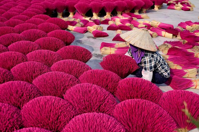A worker arranges dried incense sticks to dry in a courtyard in Quang Phu Cau village on the outskirts of Hanoi on January 21, 2025, ahead of Lunar New Year celebrations, known in Vietnam as Tet. (Photo by Nhac Nguyen/AFP Photo)