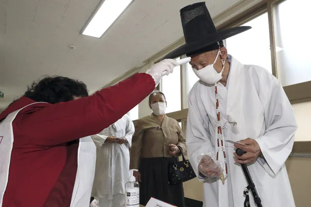 A South Korean Confucian scholar wearing a face mask to help protect against the spread of the new coronavirus has his temperature checked upon his arrival to cast his vote for the parliamentary elections at a polling station in Nonsan, South Korea, Wednesday, April 15, 2020. South Korean voters wore masks and moved slowly between lines of tape at polling stations on Wednesday to elect lawmakers in the shadows of the spreading coronavirus. (Photo by Kang Jong-min/Newsis via AP Photo)