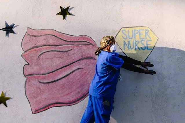A medical worker poses in front of a chalk mural outside Mount Sinai Morningside hospital in New York on May 7, 2020 during nurses appreciation week. (Photo by Nina Westervelt/Rex Features/Shutterstock)