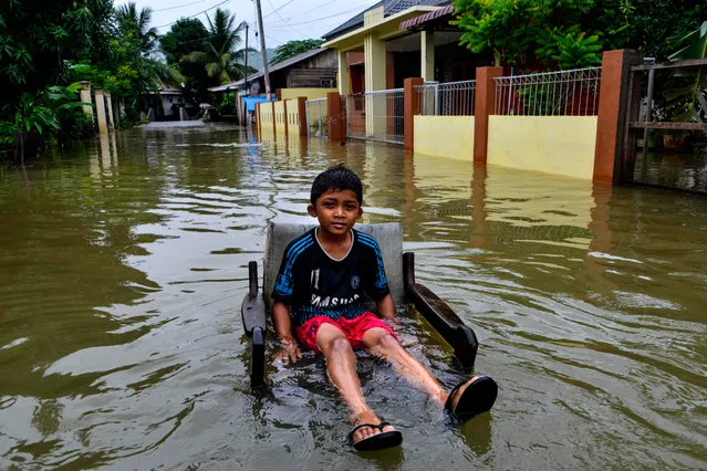 A boy sits on a chair in a flooded residential area caused by heavy rain in Banda Aceh on May 10, 2020. (Photo by Chaideer Mahyuddin/AFP Photo)