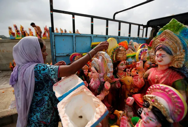 A woman loads idols of Hindu goddess Dashama, left by devotees on the banks of river Sabarmati onto a truck a day after the “Dashama” festival in Ahmedabad, India, August 12, 2016. (Photo by Amit Dave/Reuters)