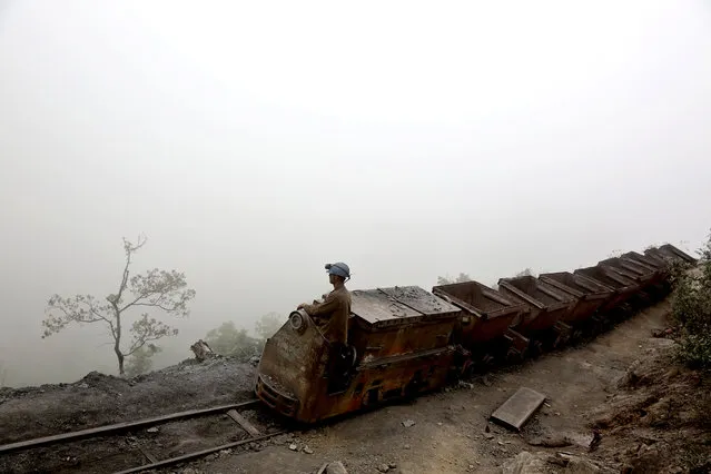 In this Thursday, May 8, 2014 photo, an Iranian coal miner moves wagons to be loaded with coal at a mine near the city of Zirab 212 kilometers (132 miles) northeast of the capital Tehran, on a mountain in Mazandaran province, Iran. International sanctions linked to the decade-long dispute over Iran's nuclear program have hindered the import of heavy machinery and modern technology in all sectors, and coal mining is no exception. (Photo by Ebrahim Noroozi/AP Photo)