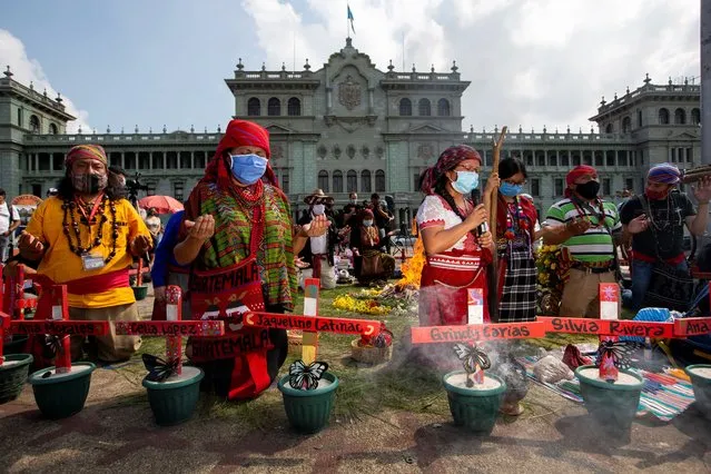 Mayan priests hold a ceremony in memorial of the late, well-known Mayan spiritual guide and natural medicine expert, Domingo Choc Che, in Constitution Plaza in Guatemala City, Wednesday, June 10, 2020. Police say they arrested four people in connection with the June 7 killing of Choc Che in the village of Chimay, in the department of Peten, after he was beaten for hours and the next day doused with gasoline and set on fire by people who believed he had been performing witchcraft at a relative's gravesite. The names on the crosses are of 41 adolescent girls killed in a fire at a government children's home in 2017. (Photo by Moises Castillo/AP Photo)