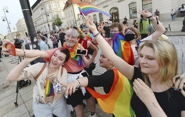 People, with Rainbow flags dance as they take part in rainbow disco flashmob in front of the Presidential Palace in Warsaw, Poland, Thursday, June 11, 2020. Polish President Andrzej Duda signed a document called Family Card which is homophobic and discriminating in the perception of the LGBT community. (Photo by Czarek Sokolowski/AP Photo)