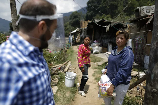 Patricia Cruz Castillo, 28, accepts a bag of donated food and household items brought by Luis Gutierrez of De La Mano Hacemos Mas (Spanish for Hand In Hand We Accomplish More), in Piedra Grande, Huixquilucan, Mexico State, Wednesday, June 17, 2020. Though the hillside community has so far felt isolated from the virus that causes COVID-19, the economic effects are widespread, with many inhabitants having lost their jobs in construction, farming, domestic work, and businesses that have been forced to close. (Photo by Rebecca Blackwell/AP Photo)