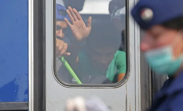 A migrant waves as he sits in a bus waiting to depart from a migrant collection point near the Serbian Hungarian border in Roszke, Hungary September 13, 2015. (Photo by Laszlo Balogh/Reuters)
