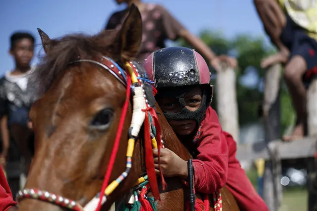 An Indonesian child jockey holds the saddlery of his horse shortly before the start during training at Panda racetrack outside Bima, West Nusa Tenggara province, Indonesia, 22 March 2015. (Photo by Mast Irham/EPA)