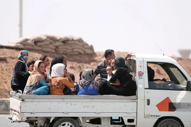 People ride on the back of pickup truck as they flee Hasaka after the Syrian government deployed warplanes to bomb the Kurdish-held areas in the city, on one of the exit points of Hasaka, Syria August 20, 2016. (Photo by Rodi Said/Reuters)