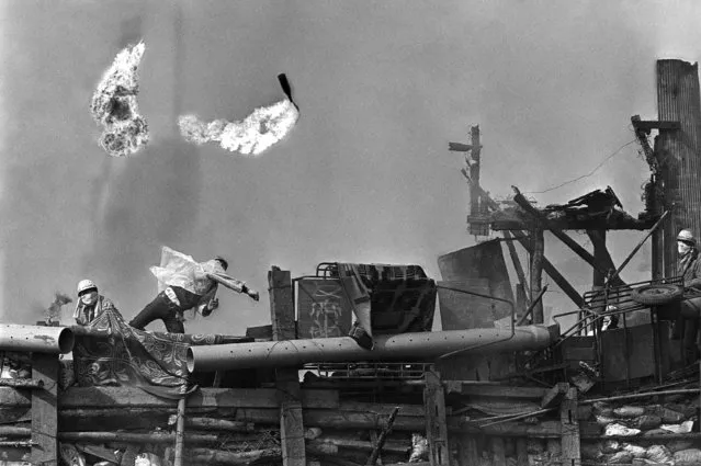 Japanese students hurl flaming Molotov cocktails at police, from a barricaded area they have built at the site of a proposed new airport, 60 miles from Tokyo, September 30, 1971. Fifty-two hundred leftist students and farmers opposed to the building of the airport fought pitched battles with police last month; three police men were killed, many injured. (Photo by Toichi Sakakibara/AP Photo)