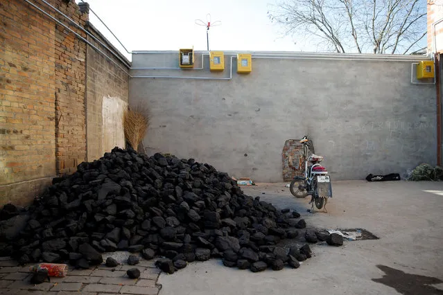 A pile of coal is seen underneath newly installed gas pipes in a courtyard in the village of Heqiaoxiang outside of Baoding, Hebei province, China, December 5, 2017. (Photo by Thomas Peter/Reuters)