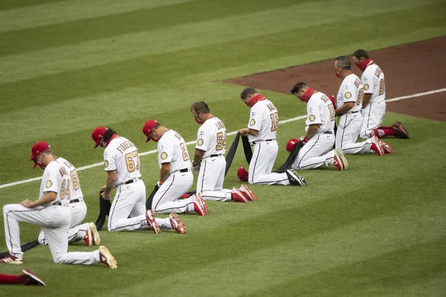 Members of Washington Nationals kneel and hold a piece of black fabric before an opening day baseball game against the New York Yankees at Nationals Park, Thursday, July 23, 2020, in Washington. (Photo by Alex Brandon/AP Photo)