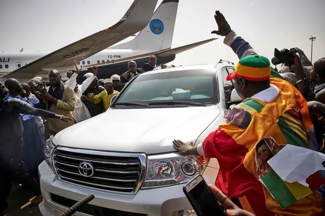 People greet former president Amadou Toumani Toure (3rd L) as he disembarks from a plane in Bamako on December 24, 2017, as he returns for the first time to Mali from living in exile in Senegal since a coup deposed him in 2012. Toure flew into the capital, Bamako, the scene of his downfall on March 22, 2012, when mutinous soldiers overthrew the government and detained him. The coup led by army captain Amadou Sanogo toppled what had been heralded as one of the region's most stable democracies, before the country's northern territory was overrun by Islamist rebels allied with Al-Qaeda. (Photo by Michele Cattani/AFP Photo)