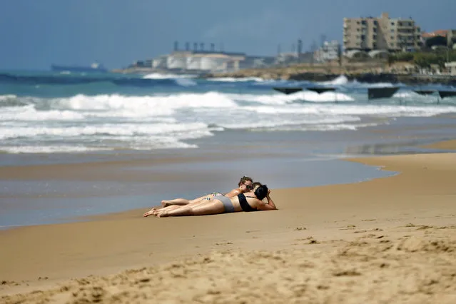Women sunbathe at Laguava Resort beach, in Rmaileh, south of Beirut, Lebanon, Saturday, June 20, 2020. Lebanon, which has had relatively low numbers of coronavirus infections and is suffering an unprecedented economic and financial crisis, has eased lockdown restrictions and reopened almost all businesses including beaches, pools, restaurants and cafes. (Photo by Bilal Hussein/AP Photo)