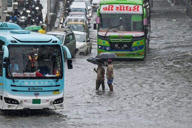 Commuters wade through a flooded street after heavy rain showers in Mumbai on May 26, 2025. Lashing rains swamped India's financial capital Mumbai on May 26 as the annual monsoon arrived some two weeks earlier than usual, according to weather forecasters. (Photo by Punit Paranjpe/AFP Photo)
