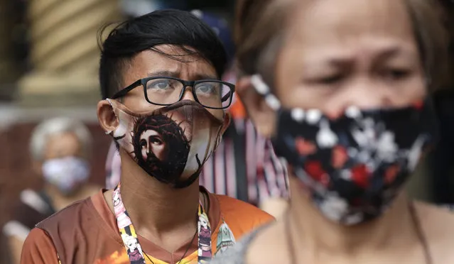 A devotee wearing a protective mask bearing the face of Jesus Christ waits outside the Minor Basilica of the Black Nazarene, popularly known as Quiapo church, as it slowly reopens its doors in downtown Manila, Philippines on Friday, June 5, 2020. President Rodrigo Duterte has expressed relief that “Filipinos are really law-abiding” and that the Philippines was not going through riots like America which would make coronavirus quarantine enforcement formidable. (Photo by Aaron Favila/AP Photo)