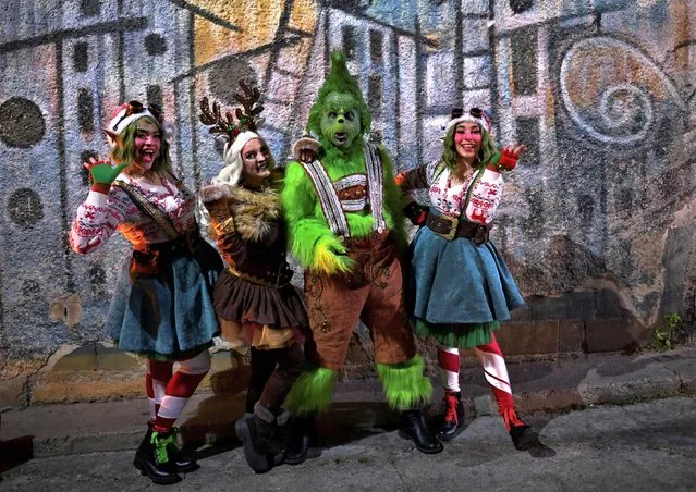 A group of volunteers dressed as elves and a man dressed as the grinch take part in a Christmas celebration organised by the NGO “Unos Venezolanos” in the neighbourhood of Petare, in Caracas, Venezuela on December 21, 2022. (Photo by Gaby Oraa/Reuters)