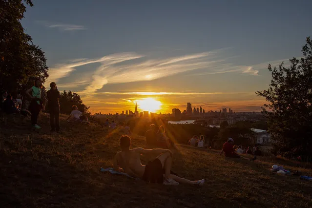 Pedestrians watch the sun set over skyscrapers on the skyline from Greenwich Park in London, U.K., on Thursday, July 30, 2020. London's best offices are forecast to plunge in value by as much as 15% this year as the coronavirus hits rents and investors' appetite for real estate. (Photo by Simon Dawson/Bloomberg via Getty Images