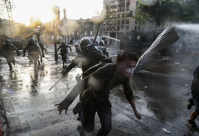 A demonstrator runs away from police during clashes at a protest against police in reaction to a video that appears to show an officer pushing a youth off a bridge the previous day at a protest, in Santiago, Chile, Saturday, October 3, 2020. (Photo by Esteban Felix/AP Photo)