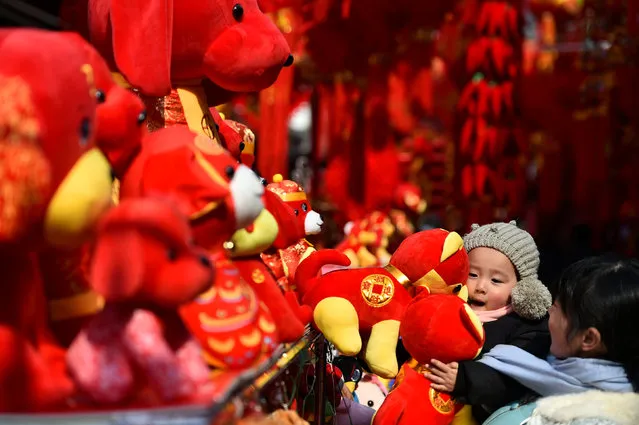 A child holds Spring Festival decorations at a market ahead of the Chinese Lunar New Year in Hefei, Anhui province, China February 3, 2018. (Photo by Reuters/China Stringer Network)
