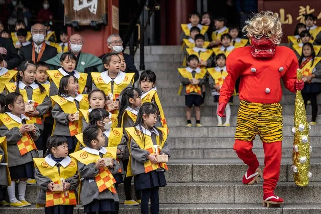 Kindergarten students look at a performer wearing a demon-like mask and costume during a bean-throwing ceremony to drive away evil spirits and bring good luck at the annual Setsubun Festival at Sensoji Temple in Tokyo on February 3, 2023. (Photo by Yuichi Yamazaki/AFP Photo)