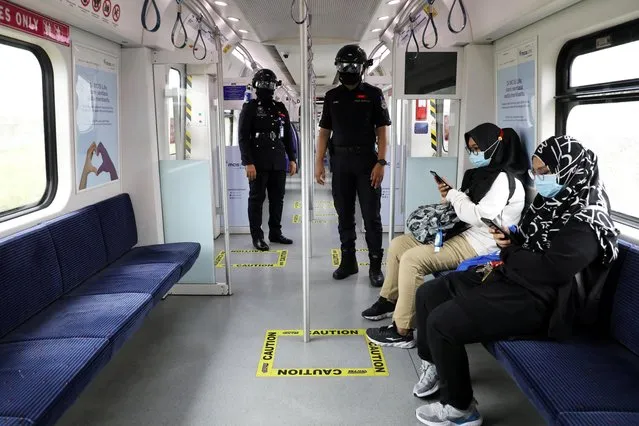 Auxiliary police officers wearing “Smart Helmet”, a portable thermoscanner that can measure the temperature of passengers at a distance, patrol inside a commuter train, amid the coronavirus disease (COVID-19) outbreak in Kuala Lumpur, Malaysia on October 14, 2020. (Photo by Lim Huey Teng/Reuters)