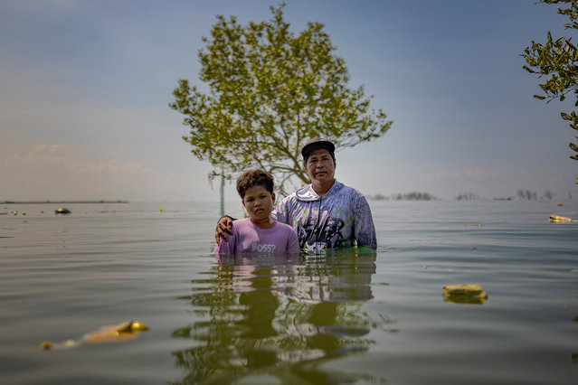 William Gregorio and his son Yamry pose for a portrait where their ancestral home used to stand, now submerged in seawater amid rising tides on August 12, 2025 in Pugad Island, Hagonoy, Philippines. In the Philippines’ coastal communities, the water has been rising for years—a slow, relentless encroachment fueled by melting ice sheets in Antarctica, the sinking of land from decades of unchecked groundwater extraction, and the swelling seas of a warming planet. But residents say the sharpest surge came with large-scale reclamation and other man-made coastal developments, which have altered currents and forced the tide farther inland. Now, even the gentlest tide can unleash deep floods, drowning streets and homes in minutes, a daily reminder of how human activity can accelerate a disaster already set in motion by climate change. (Photo by Ezra Acayan/Getty Images)